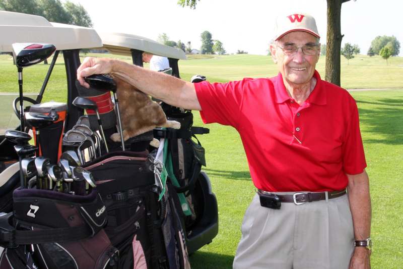an old man holding a golf bag