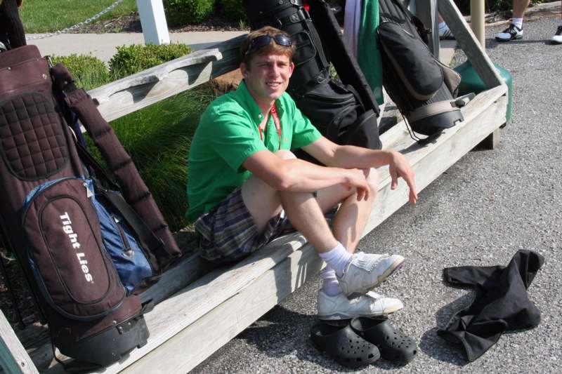 a man sitting on a bench with golf bags