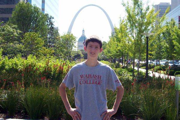 a boy standing in front of a arch