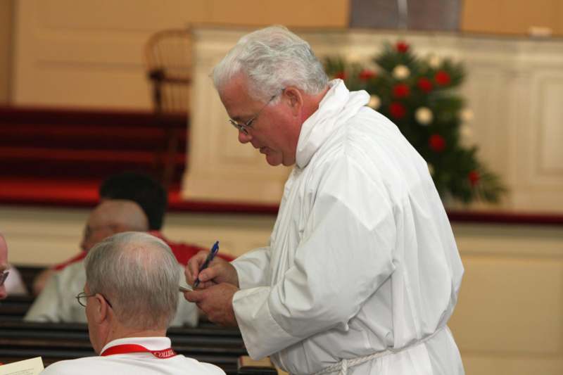 a man in a white robe cutting a man's hair