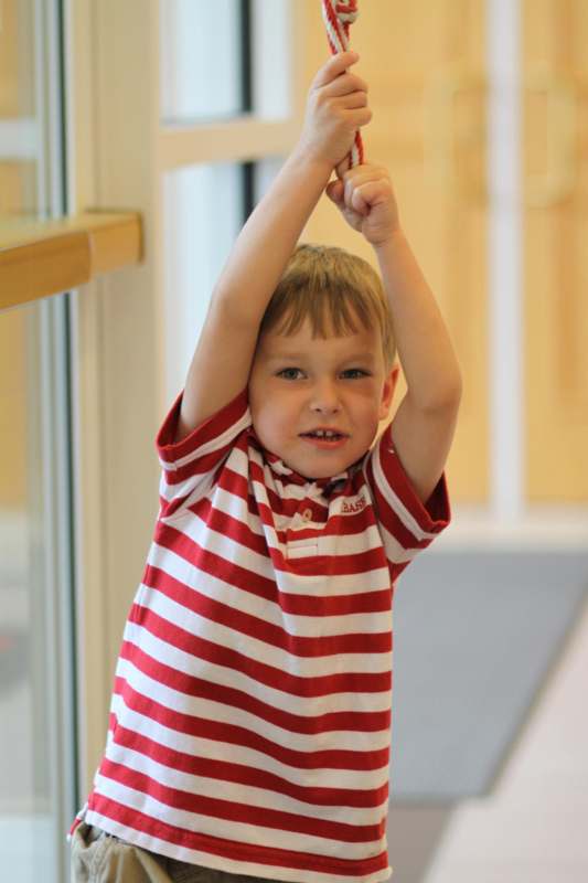 a boy holding up a red and white striped shirt