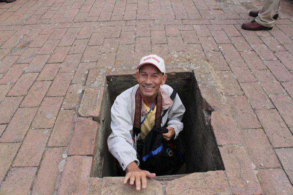 a man in a hole in a brick floor