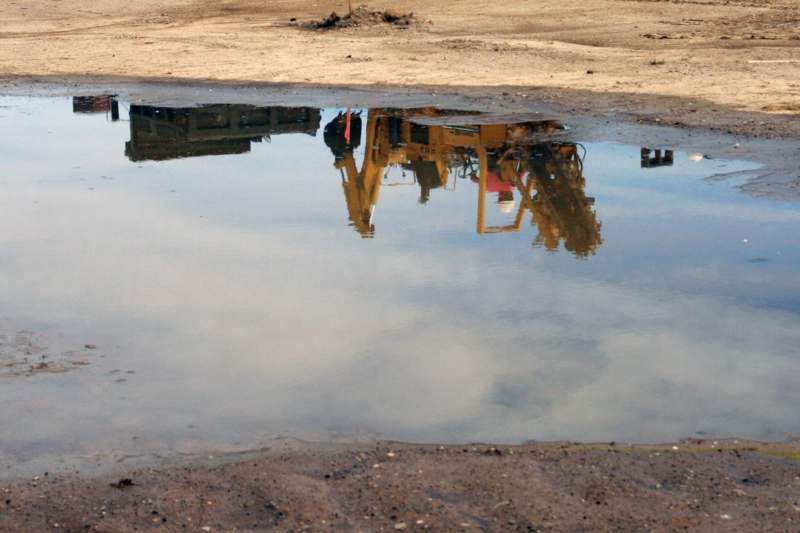 a reflection of a crane in a puddle