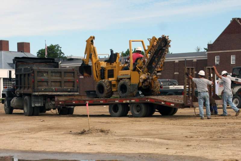 a man standing on a trailer with a bulldozer