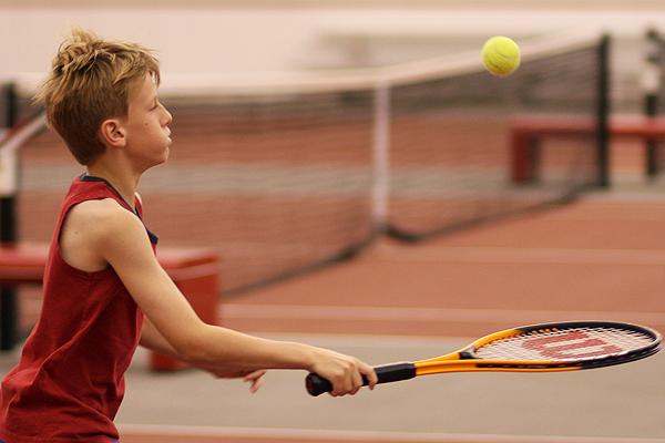 a boy hitting a tennis ball with a racket