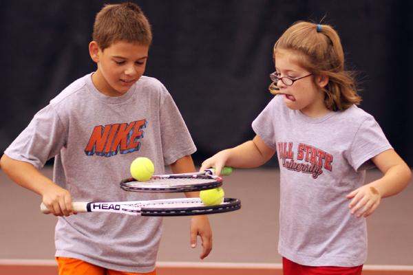 a boy and girl holding tennis rackets
