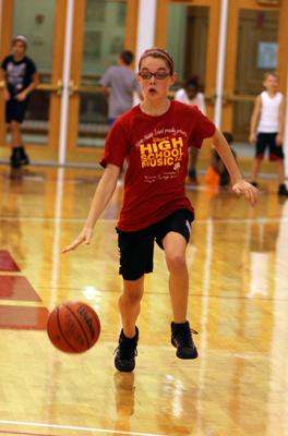 a boy playing basketball in a gym