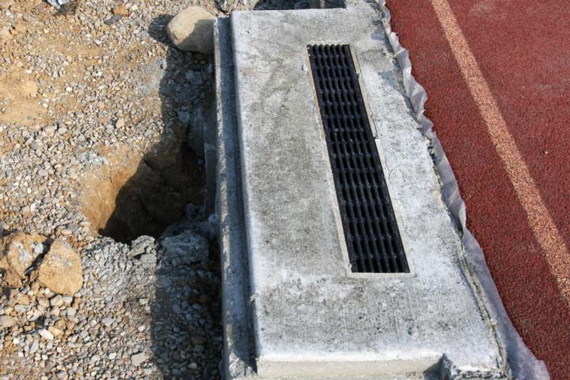 a concrete drain with a hole in the ground