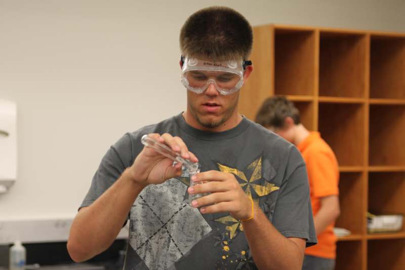 a man wearing safety goggles and holding a tube