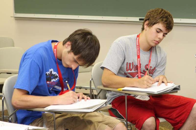 a couple of young men writing in a notebook