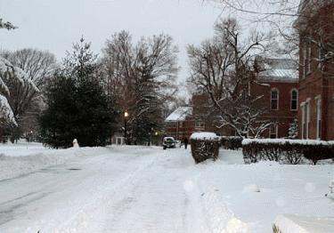 a snow covered street with a house and trees