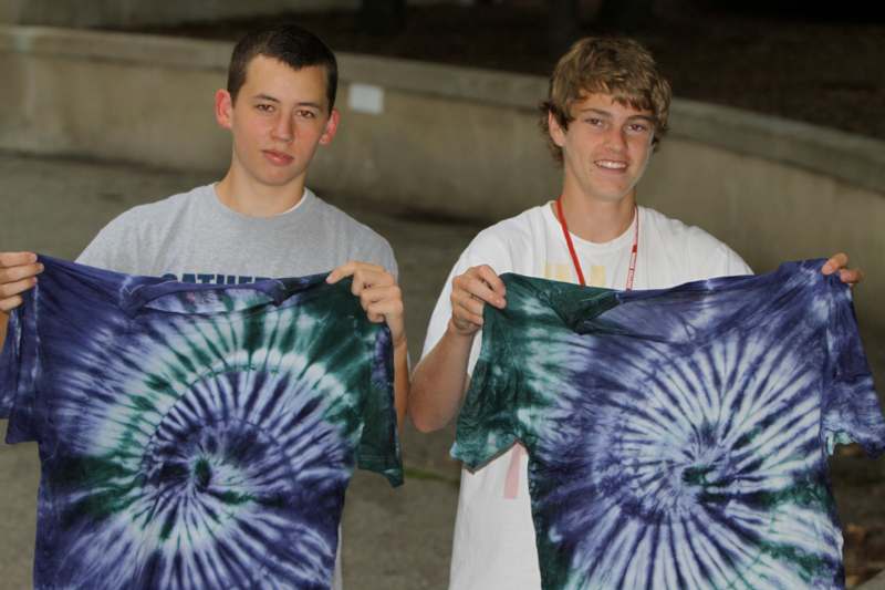 two men holding up tie dye shirts