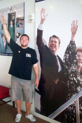 a man standing next to a poster of a man with his arms raised