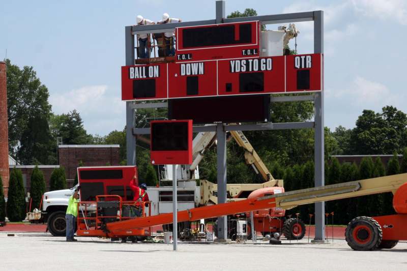 a large scoreboard with a crane and a man standing next to it