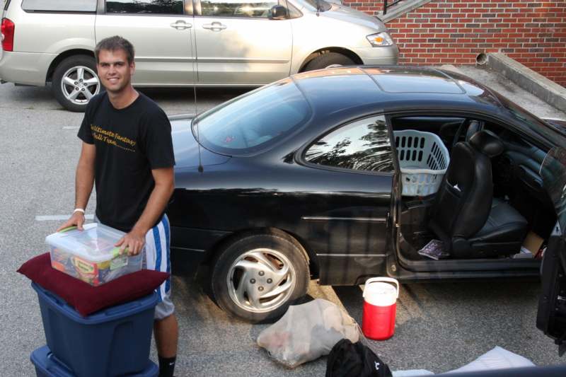a man standing next to a car with a basket full of stuff