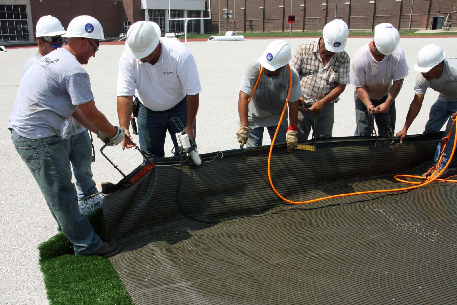 a group of men wearing hardhats working on a tarp