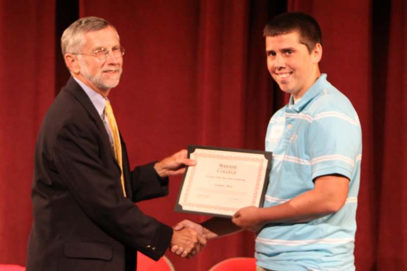 a man shaking hands with a man holding a certificate