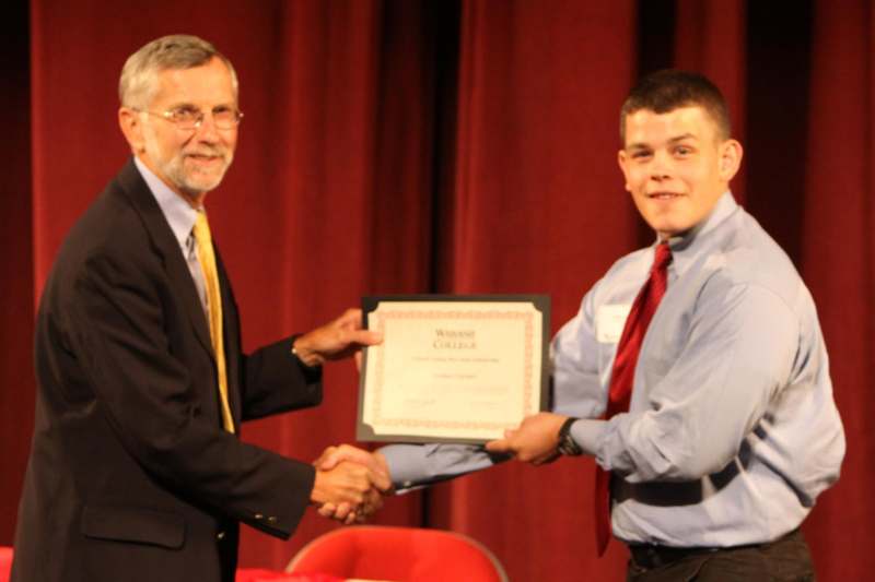 a man shaking hands with a man holding a certificate