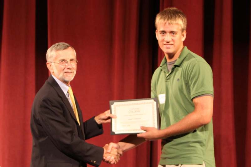 a man shaking hands with a man with a certificate