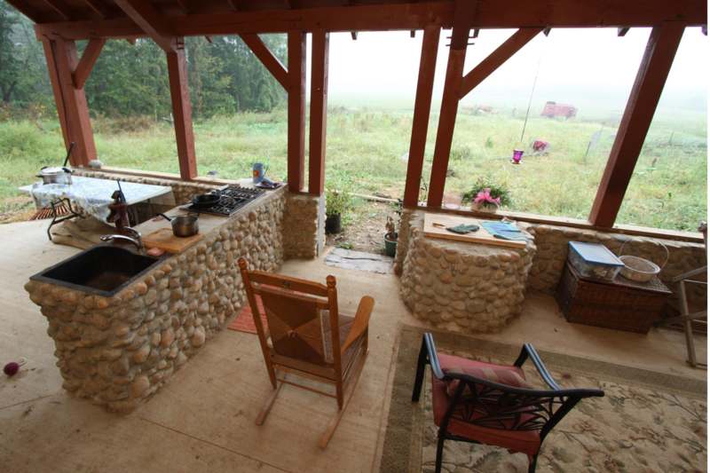a patio with a stone kitchen and a rocking chair