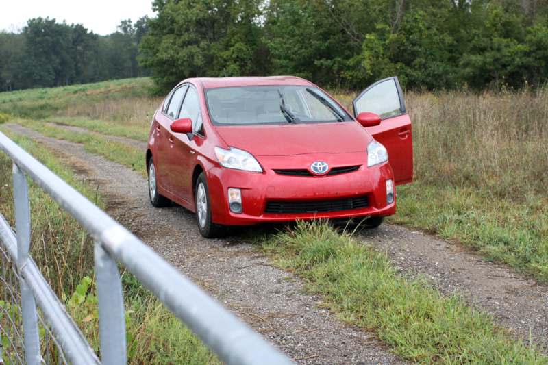 a red car with its door open on a dirt road