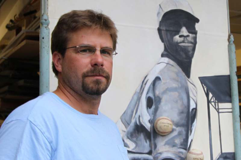 a man standing in front of a painting of a baseball player