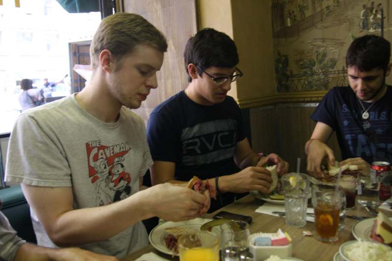 a group of men sitting at a table eating food