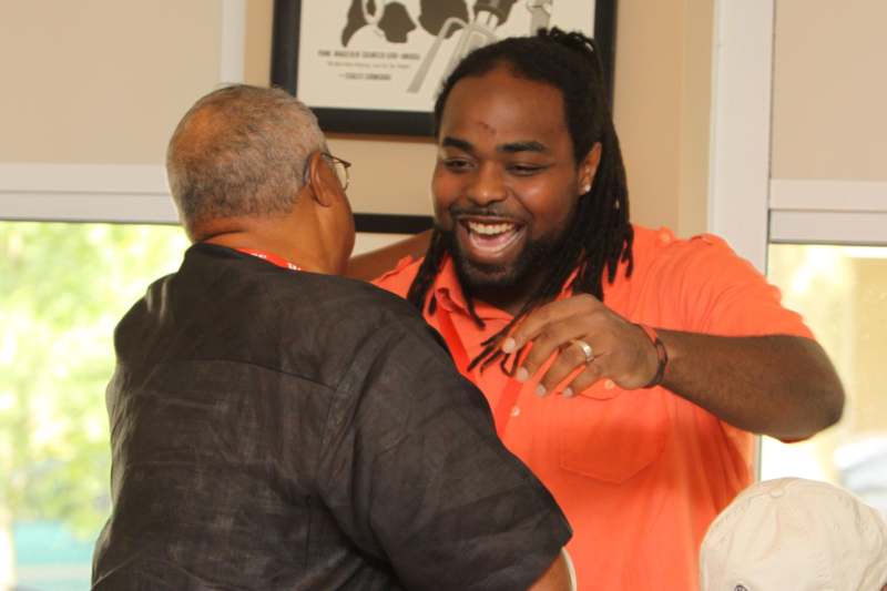 a man in an orange shirt with dreadlocks smiling