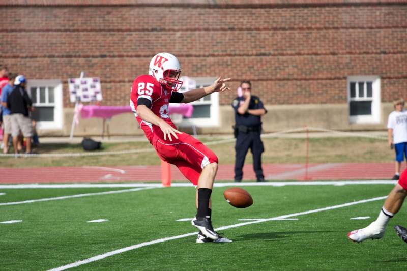 a football player in red and white uniform kicking a football