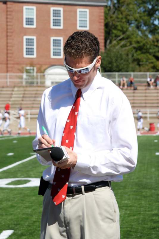 a man in a white shirt and red tie writing on a clipboard