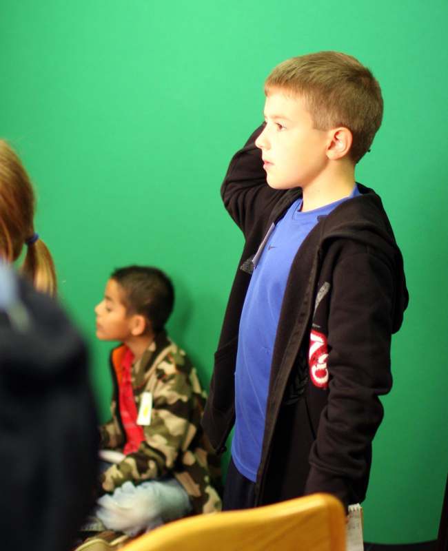 a boy standing in front of a green wall