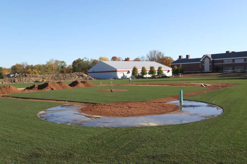 a baseball field with dirt and a puddle