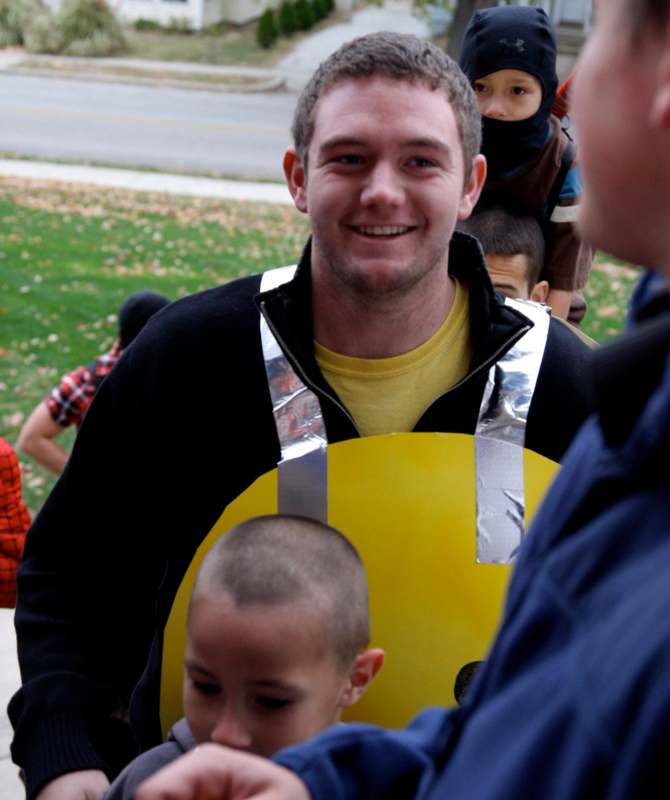 a man wearing a yellow vest with a yellow smiley face and a group of kids