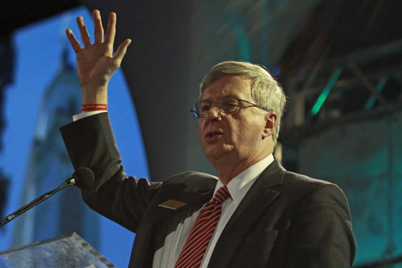 a man in a suit and tie raising his hand