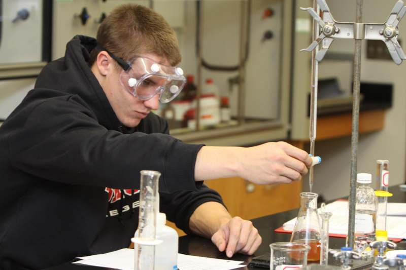 a man wearing goggles and holding a pipette