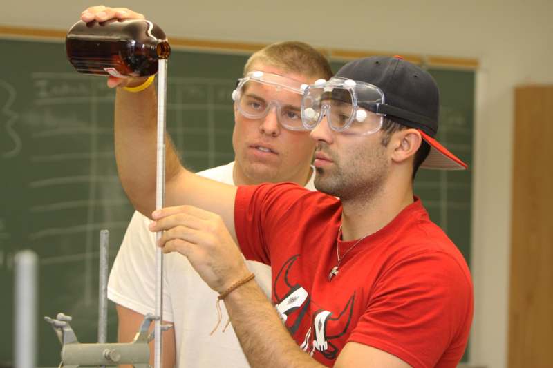 a group of men wearing safety goggles and holding a bottle