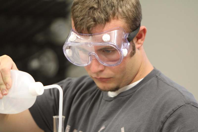 a man wearing safety goggles and looking at a tube
