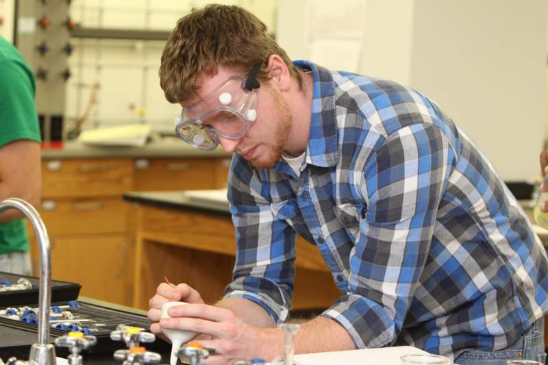 a man wearing safety goggles and working on a white object