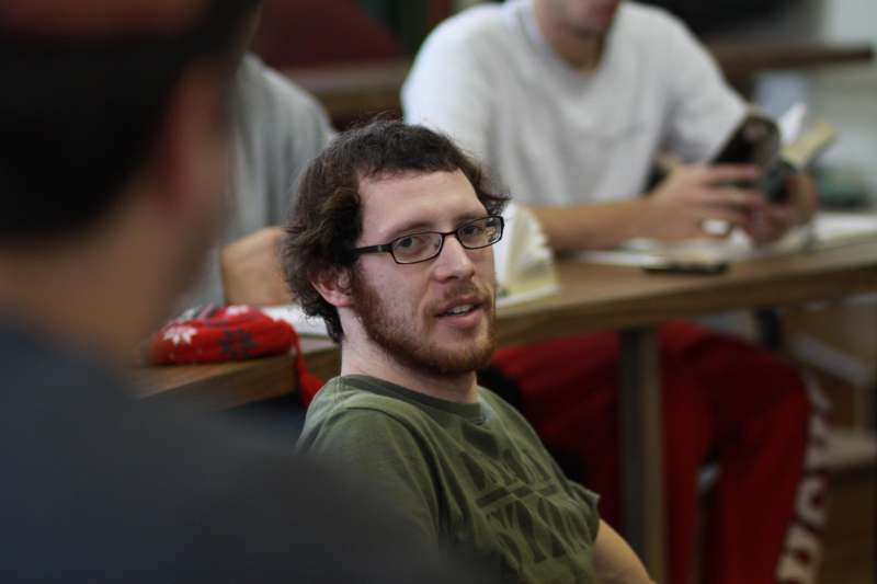 a man in glasses sitting in a classroom