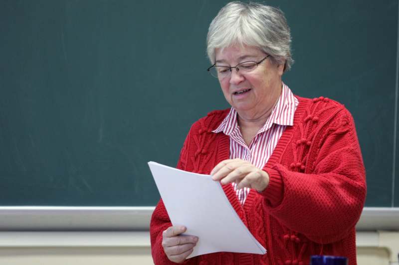 a woman in a red sweater reading a piece of paper