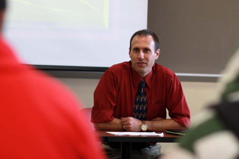 a man in a red shirt and tie sitting at a table