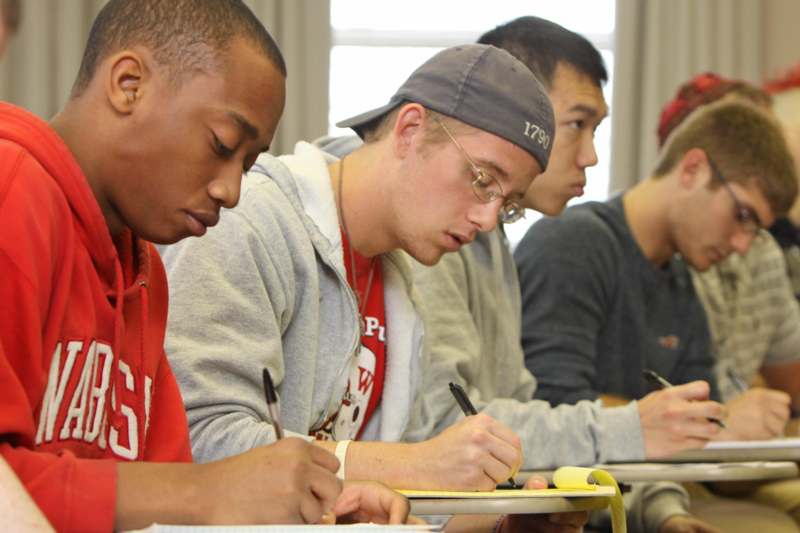 a group of young men writing on paper
