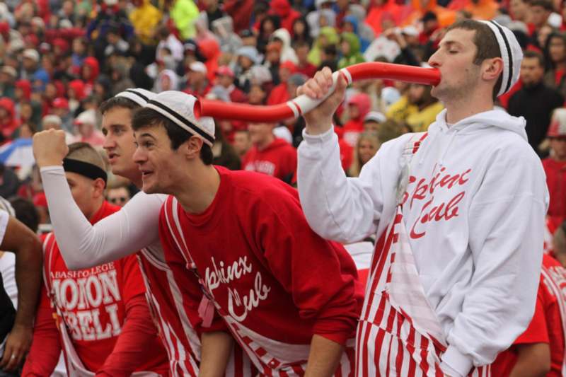 a group of men in red and white striped shirts blowing a red tube into their mouth