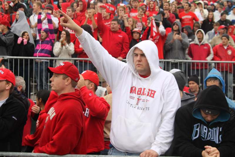 a man in a white hoodie pointing at a crowd