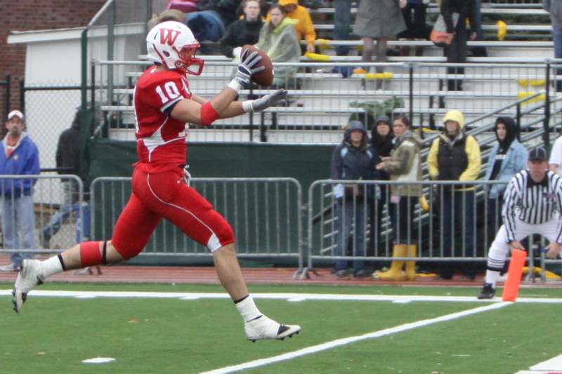 a football player in red uniform running with a football in the air