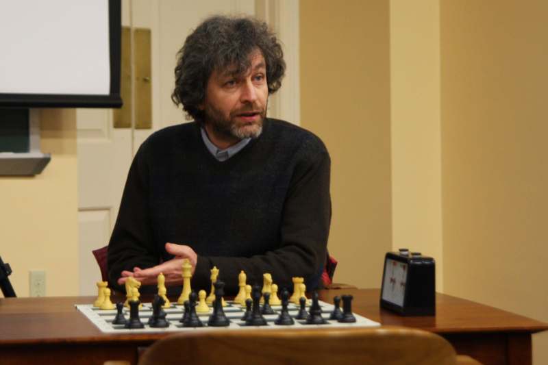 a man sitting at a table with chess pieces