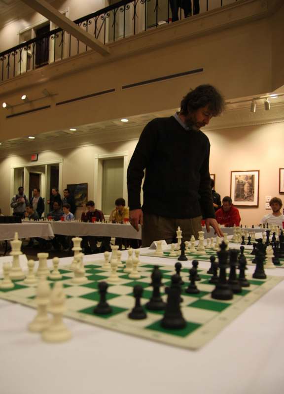 a man standing in front of a chess board