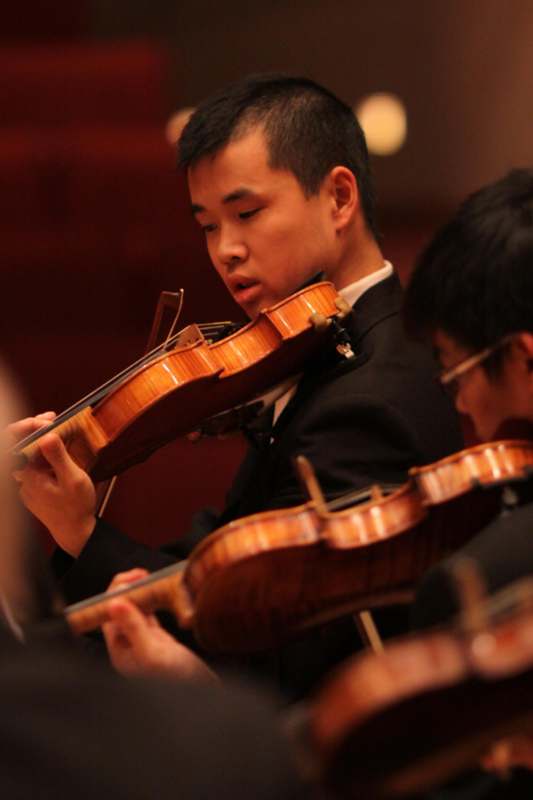 a man playing violin in a orchestra