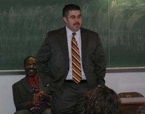 a man in a suit standing in front of a chalkboard