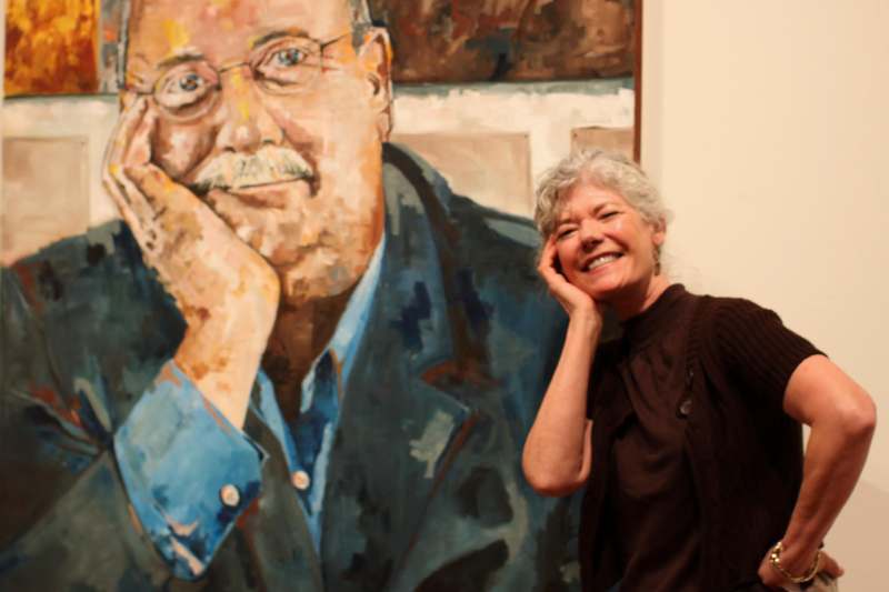 a woman smiling next to a painting